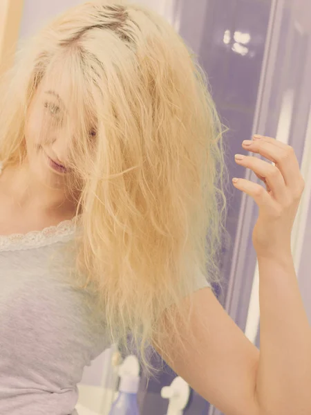 Close up portrait of funny playful female having beautiful blonde dyed fluffy hair. Haircare concept.