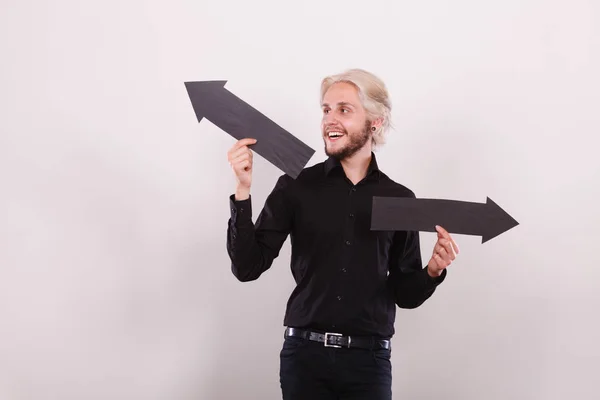 Planning, directions, choices concept. Man holding black arrow pointing left and right, opposite directions. Indoor shot on light background