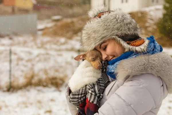 Genç bir kadın soğuk kış gününde en iyi arkadaşını sıcak battaniye eşarbına sardı. Hayvan koruma programı. Evlat edinme kavramı