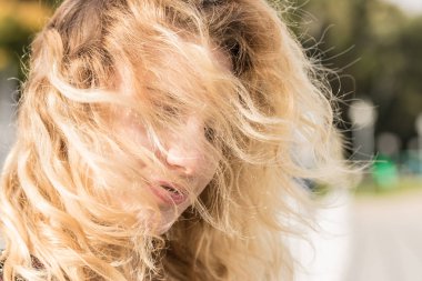 Mutlu portre sarışın kadın gülümsüyor. Neşeli erkek açık olan Rüzgar yürüyüş güneş ışığı altında saç tousled olumlu olmak