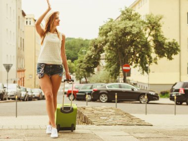 Otostop ve seyahat. Güzel gülümseyen şirin kızla yeşil valizi Bagaj Bagaj için araba bekliyor. Tüm dünyada seyahat şapkalı kadın hitch hiker.