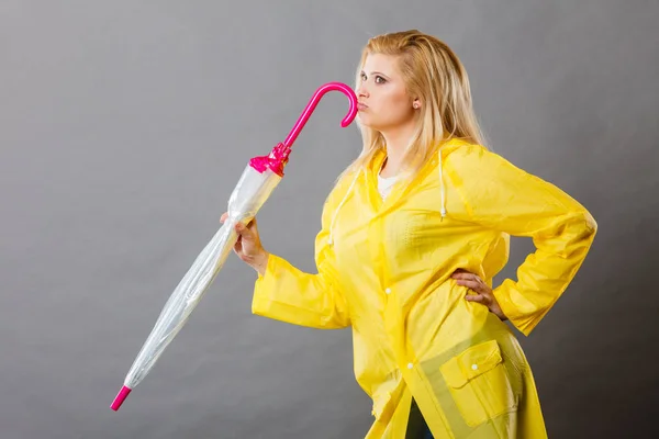Thinking woman wearing raincoat holding closed umbrella — Stock Photo, Image