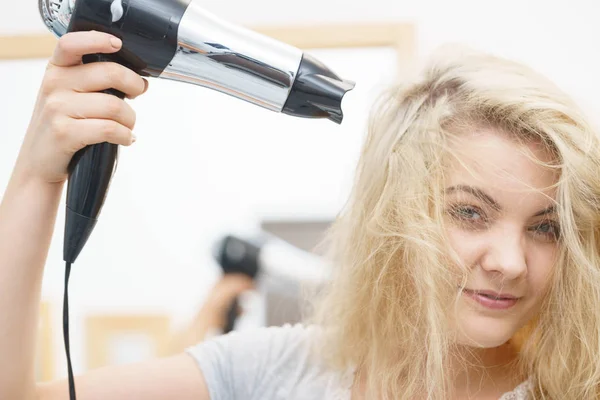 Blonde woman using hair dryer — Stock Photo, Image