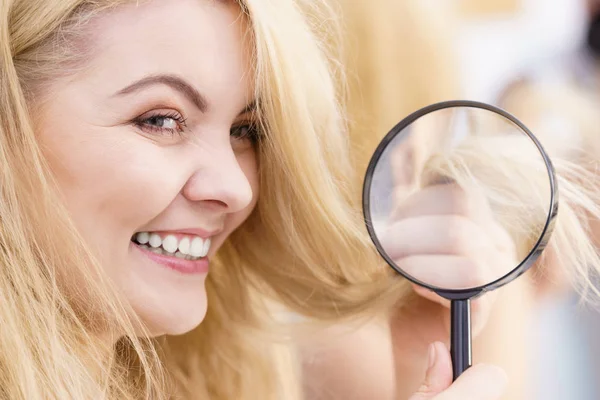 Mujer feliz mirando a través de la lupa en el cabello —  Fotos de Stock