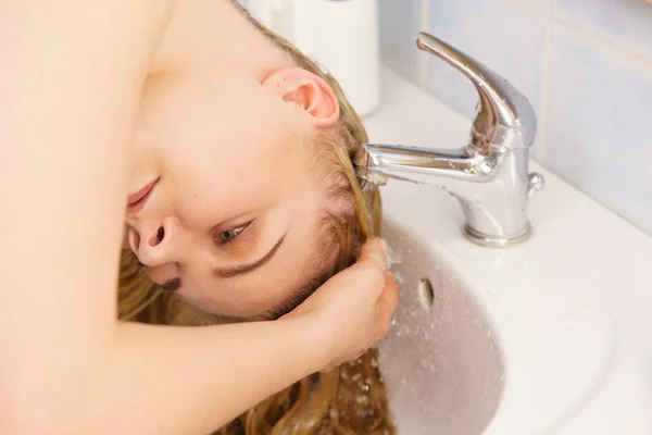 Женщина моет волосы в ванной раковине — стоковое фото