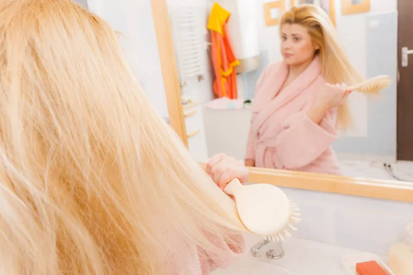 Женщина в халате расчесывает волосы — стоковое фото