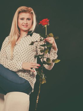 Koltukta oturan kız kırmızı gül, karanlık üzerinde tutar..