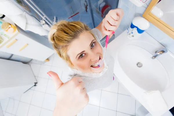 Mulher escovando os dentes de limpeza no banheiro — Fotografia de Stock