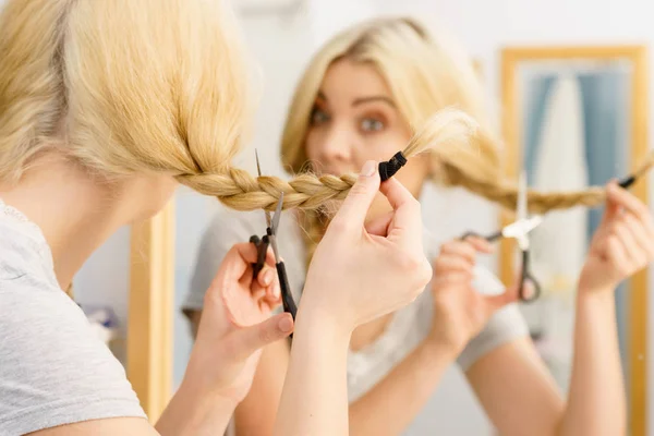 Mujer cortando cabello trenzado rubio — Foto de Stock