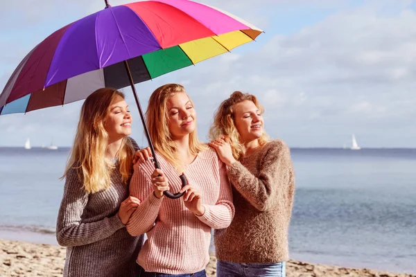 Trzy kobiety pod kolorowym parasolem — Zdjęcie stockowe