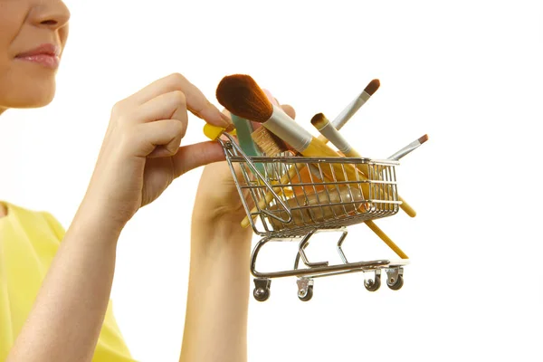 Woman holding shopping cart with make up brushes — Stock Photo, Image