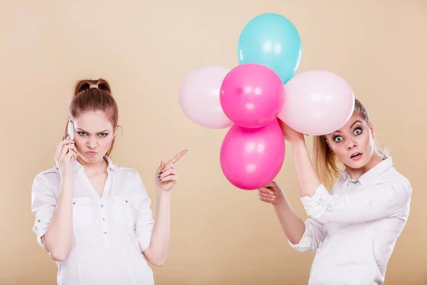 Två tjejer med mobiltelefon och ballonger — Stockfoto