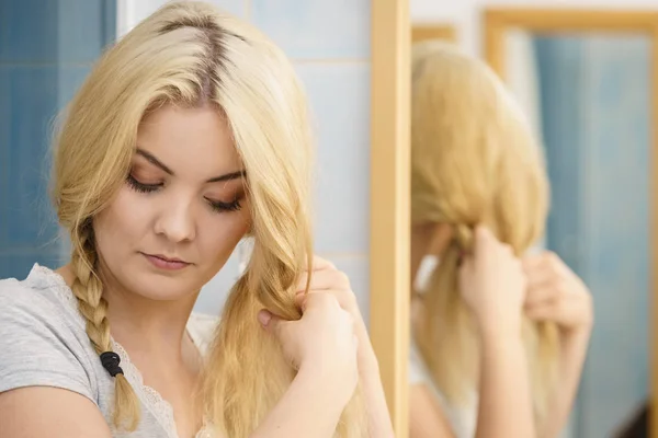 Женщина делает косички на светлых волосах — стоковое фото