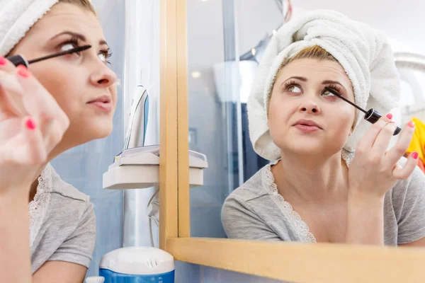 Mujer en el baño aplicando rímel en las pestañas — Foto de Stock