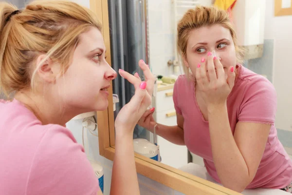 Mujer aplicando crema facial con el dedo — Foto de Stock