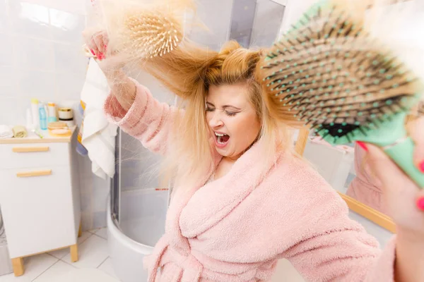 Zszokowana kobieta ubrana szlafrok szczotkowanie jej włosy — Zdjęcie stockowe