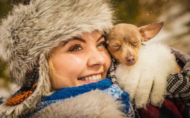 Küçük köpeğini kışın ısınma kadın kucaklama