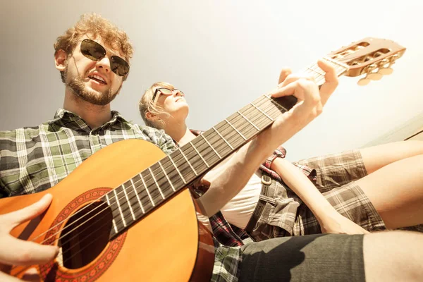 Young man hipster playing guitar for woman. — Stock Photo, Image