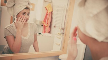 Bir kadın aynadaki yansımasına bakıyor.