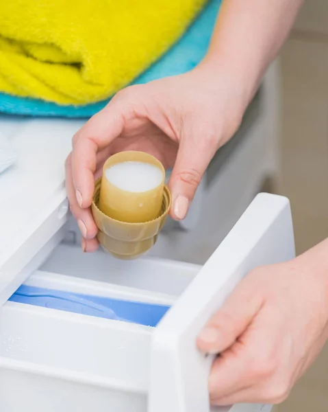 Person pouring fabric softener into washing machine