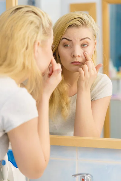 Vrouw kijkt naar haar huid in spiegel — Stockfoto