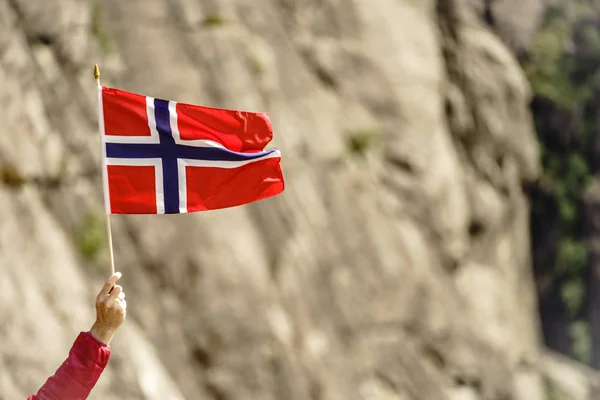 Turista con bandiera norvegese nelle montagne rocciose — Foto Stock