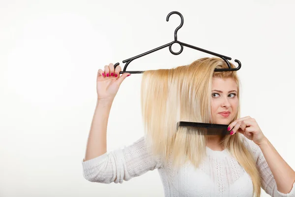 Mulher loira segurando o cabelo no cabide de roupas — Fotografia de Stock