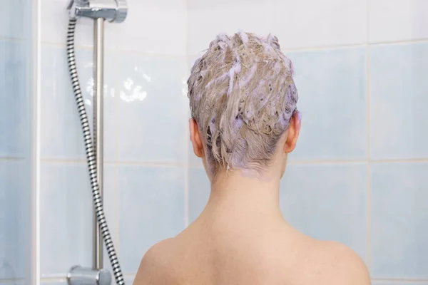 Mujer bajo la ducha con espuma de color en el cabello — Foto de Stock