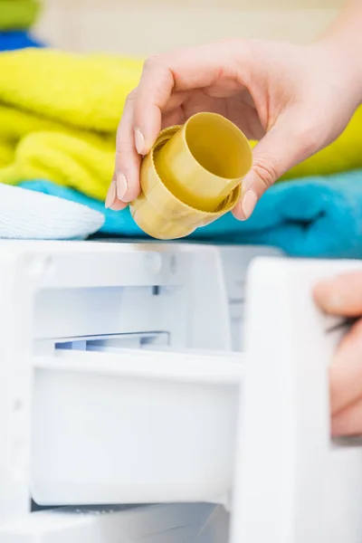 Pessoa derramando amaciador de tecido na máquina de lavar roupa — Fotografia de Stock