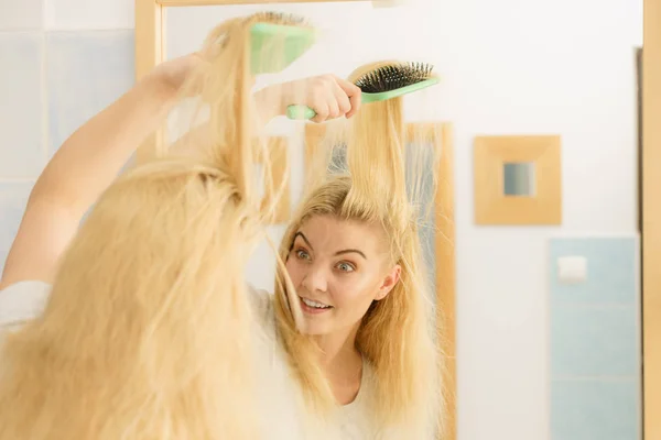 Mujer cepillándose el pelo rubio en el baño — Foto de Stock