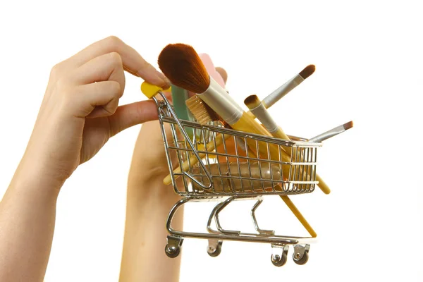 Mujer sosteniendo carrito de compras con pinceles de maquillaje —  Fotos de Stock