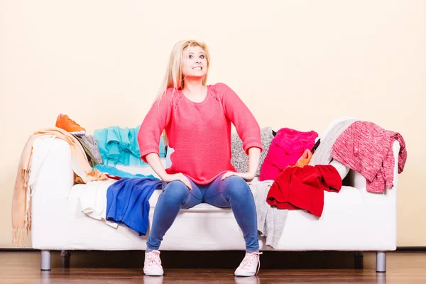 Woman does not know what to wear sitting on couch Stock Photo