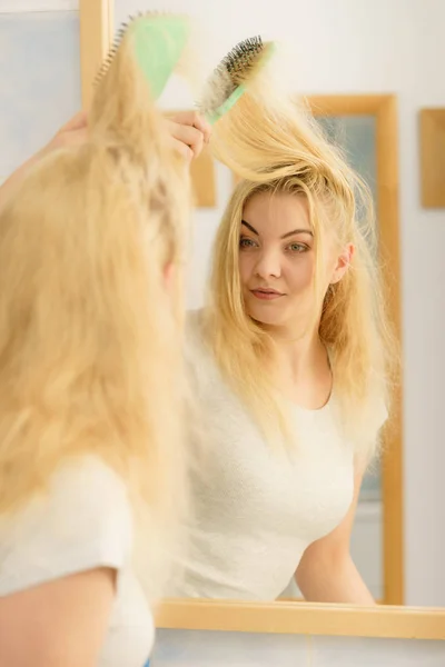 Mulher escovando seu cabelo loiro no banheiro — Fotografia de Stock