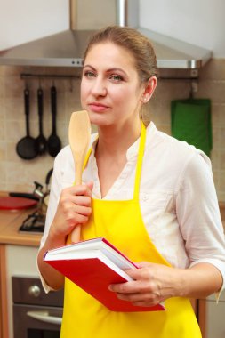 Ev hanımı kadın mutfakta yemek kitabı ile.