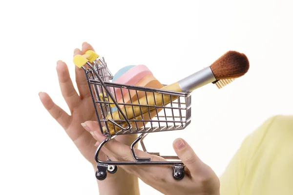 Mujer sosteniendo carrito de compras con pinceles de maquillaje — Foto de Stock