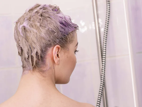 Vrouw onder de douche met gekleurde schuim op haar — Stockfoto