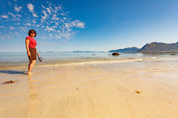 Woman walking on sandy beach, Lofoten Norway