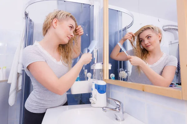 Mujer peinando su pelo largo en el baño — Foto de Stock