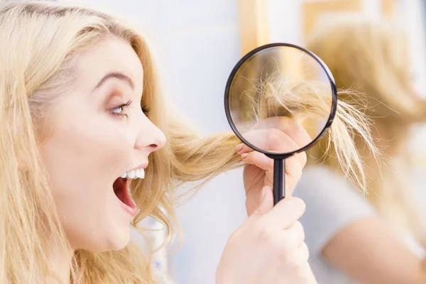 Happy woman looking through magnifer at hair — Stock Photo, Image