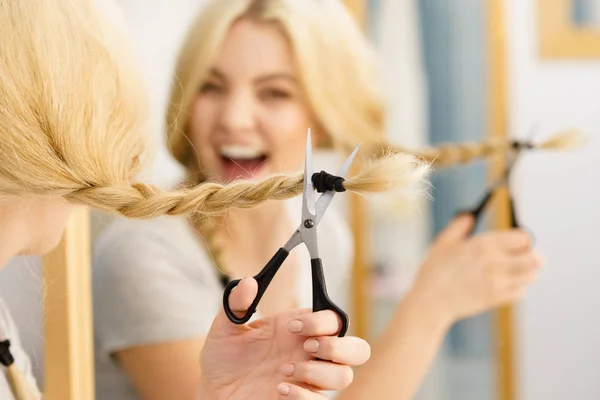 Vrouw snijden vlecht blond haar — Stockfoto