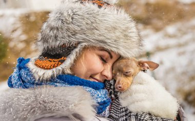 Küçük köpeğini kışın ısınma kadın kucaklama