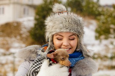Küçük köpeğini kışın ısınma kadın kucaklama