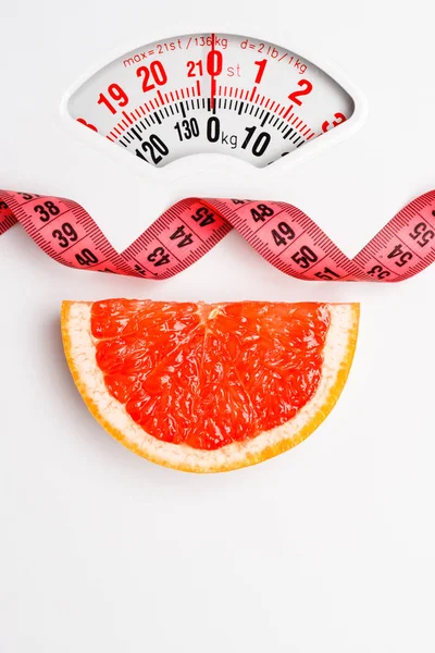 Grapefruit with measuring tape on weight scale. Dieting — Stock Photo, Image