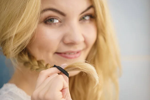 Vrouw maken vlecht op blonde haren — Stockfoto