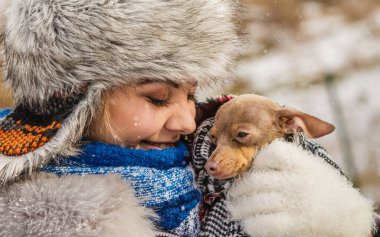 Küçük köpeğini kışın ısınma kadın kucaklama