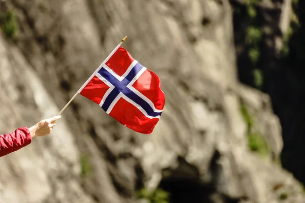 Turista con bandiera norvegese nelle montagne rocciose — Foto Stock