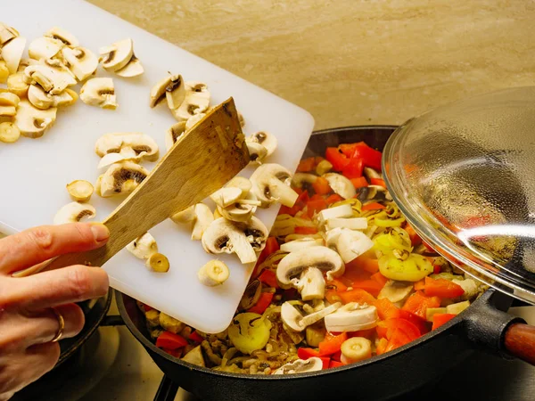 Ajouter des champignons à la casserole de légumes . — Photo