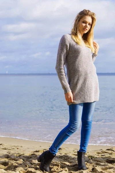 Kvinna i tröja promenader på stranden — Stockfoto