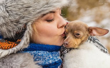 Küçük köpeğini kışın ısınma kadın kucaklama