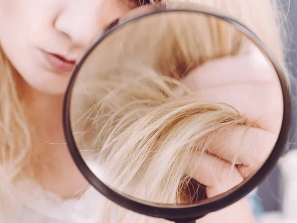 Mulher olhando para o cabelo termina através de lupa — Fotografia de Stock